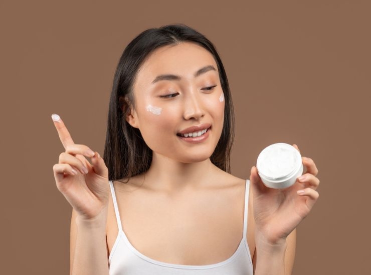 Donna coreana applica una crema sul viso