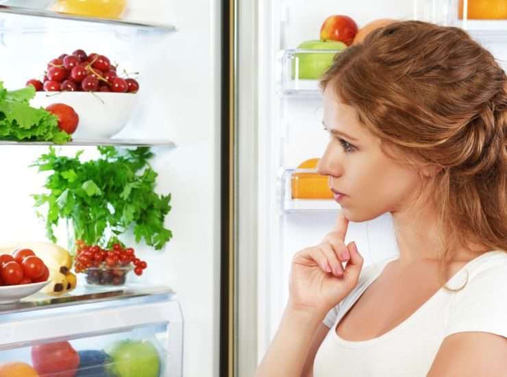 Ragazza che sceglie il cibo davanti al frigorifero 